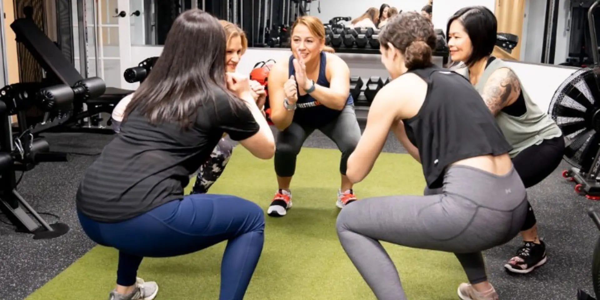 Five women doing squats together at Free2Be Fitness